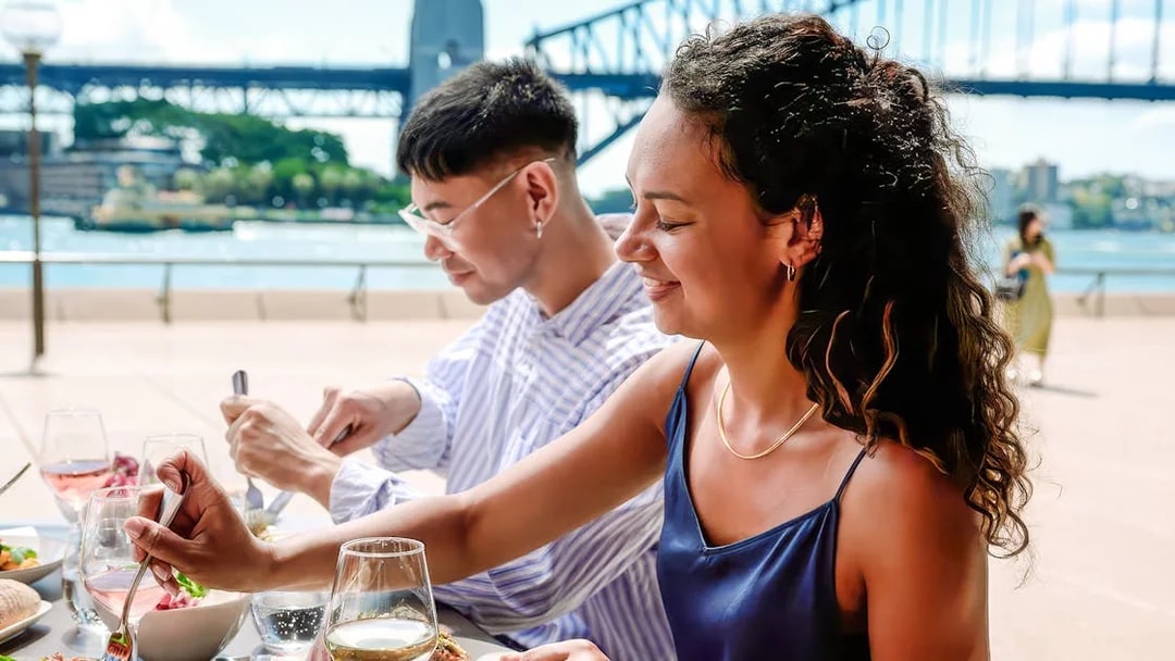 People dining at Midden by Mark Olive with Sydney Harbour Bridge in the background.