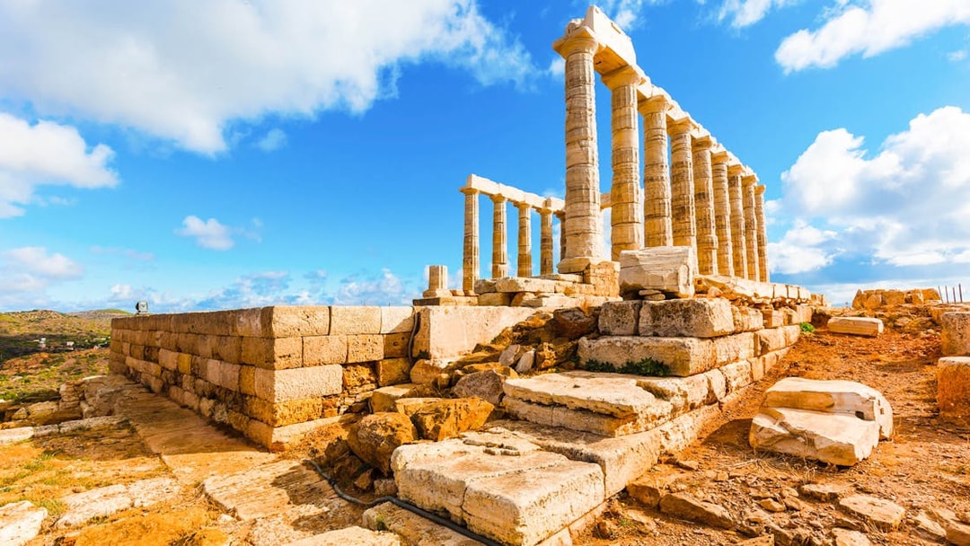 Temple of Poseidon ruins at Cape Sounion under a blue sky, part of guided tour from Athens.