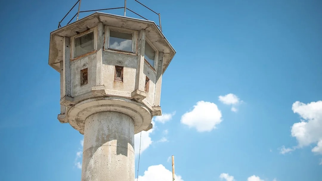 Watchtower from the Cold War era in Berlin against a blue sky.