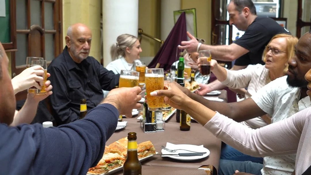 Group toasting with drinks at a table during Valletta food tour.
