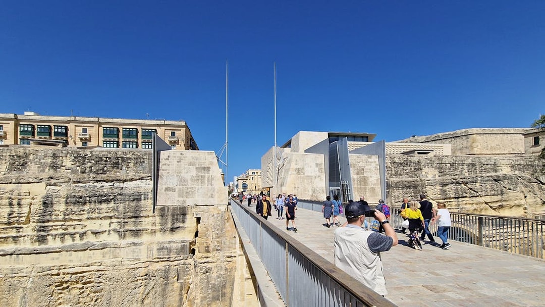 Visitors walking on a bridge towards Valletta's historic city gate during a food tour.