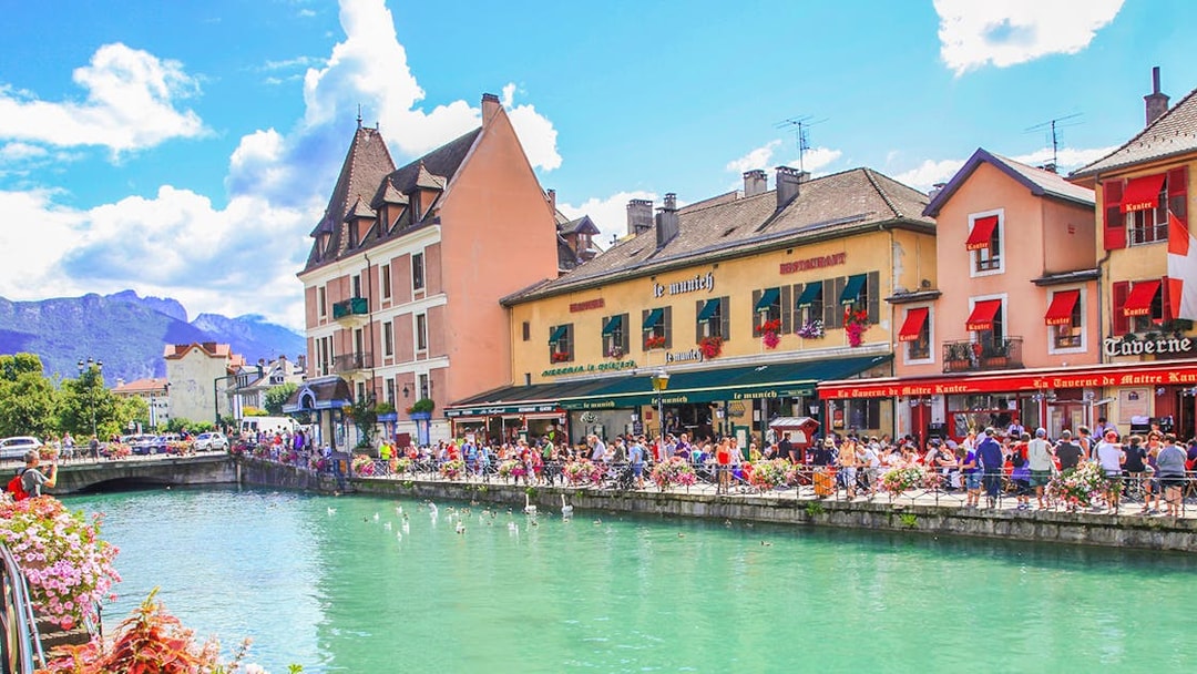 Canal in Annecy with colorful buildings and people enjoying the waterfront.