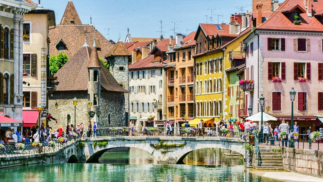Colorful buildings and a stone bridge over a canal in Annecy, France.