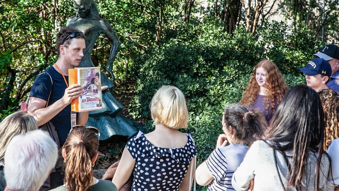 Tour guide explaining Montjuïc history to a group near a statue.