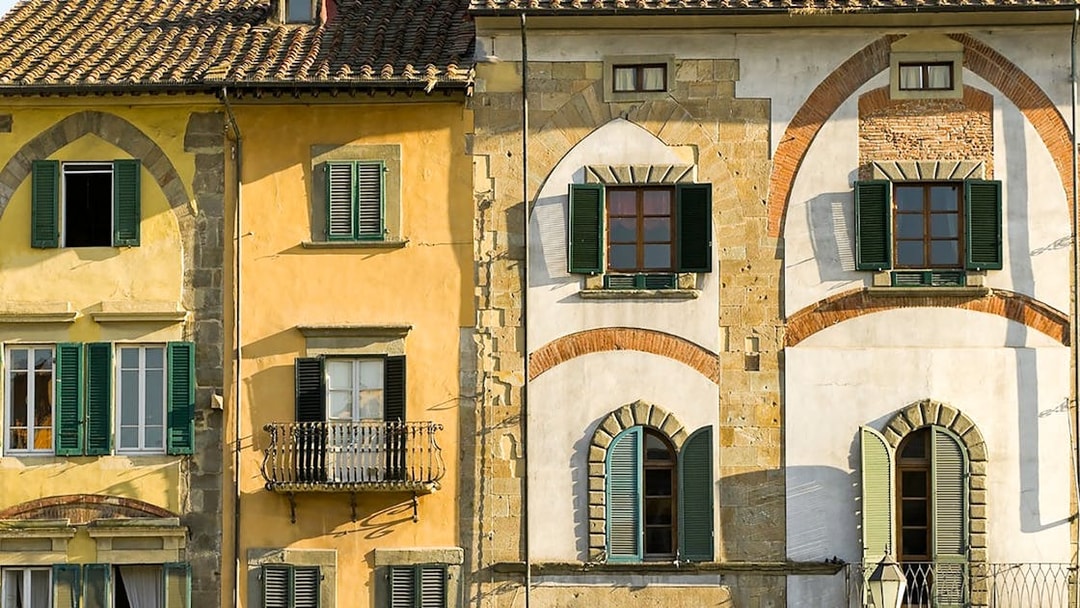 Colorful historic buildings with arched windows in Pisa, Italy.