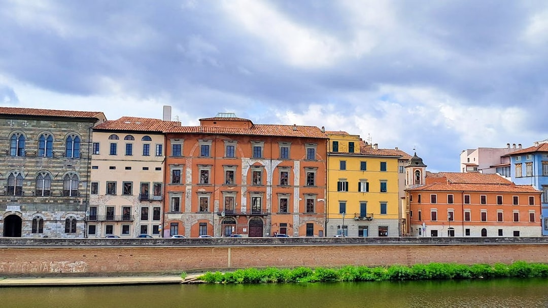 Colorful historic buildings along the Arno River in Pisa, Italy.