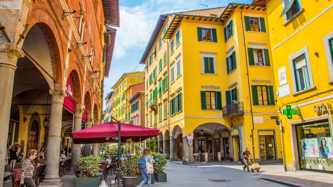 Street view of colorful buildings and outdoor cafes in Pisa during a guided walking tour.