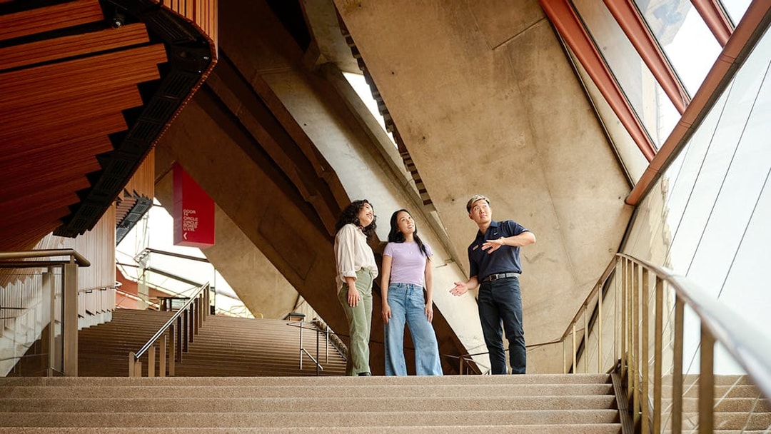 Tour guide explaining architecture to visitors inside Sydney Opera House.