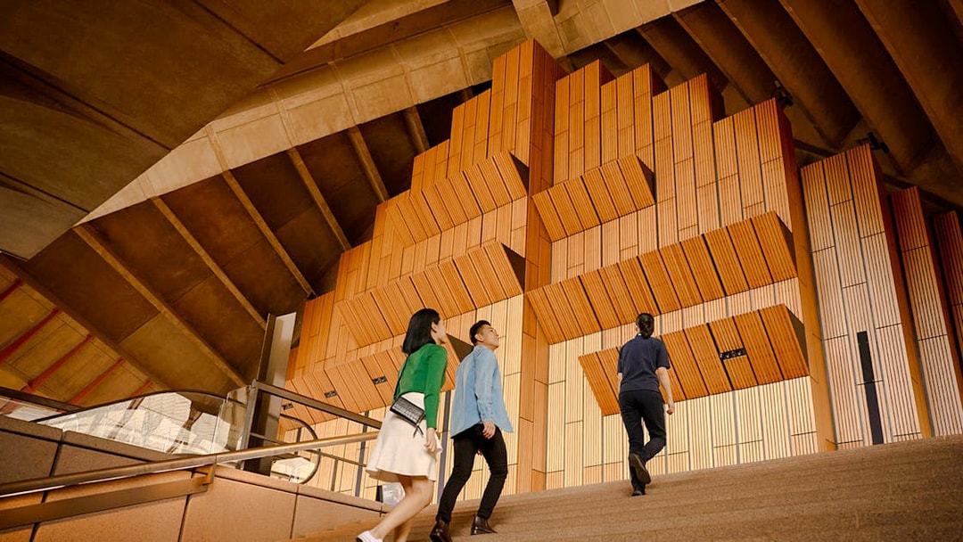 Visitors ascending steps inside Sydney Opera House during guided walking tour.