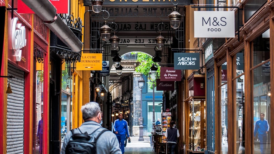 Guided tour through Paris's historic covered passages with shops and signs.