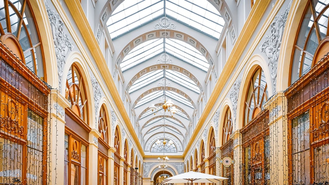 Covered passage with ornate arches and glass ceiling in Paris.