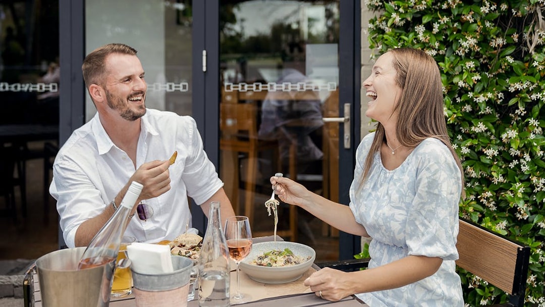 Couple enjoying wine and food at an outdoor table during a Hunter Valley wine tasting tour.