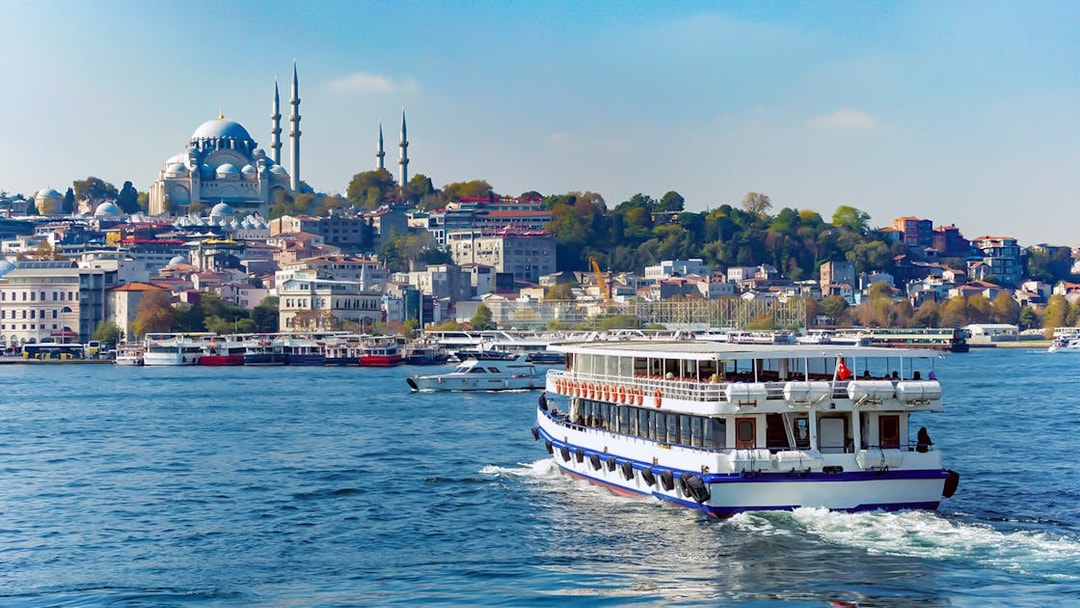 Bosphorus cruise ship sailing with Istanbul skyline and mosque in the background.