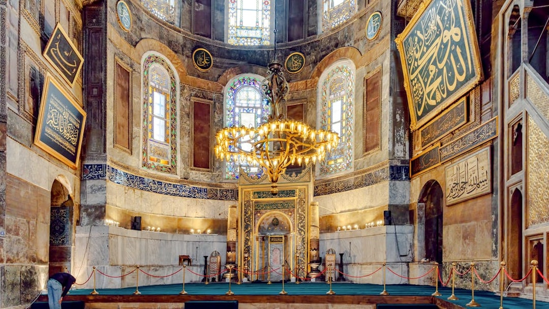Hagia Sophia interior with ornate chandelier and Arabic calligraphy on walls.