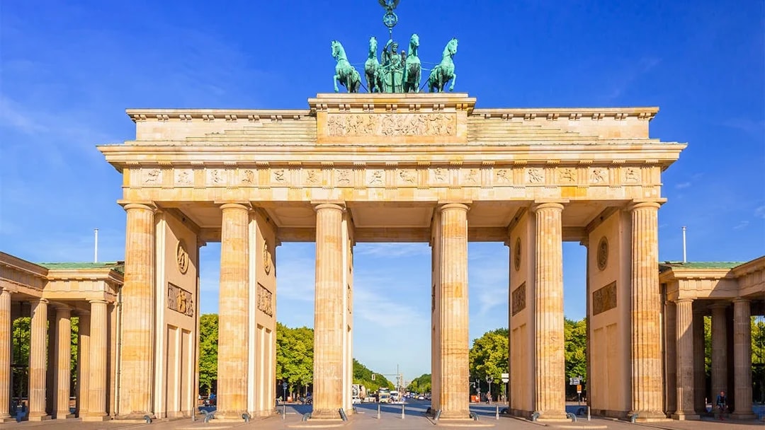 Brandenburg Gate in Berlin under a clear blue sky, viewed from the front.