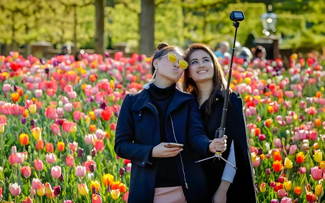 Visitors taking a selfie among colorful tulips at Keukenhof Gardens.