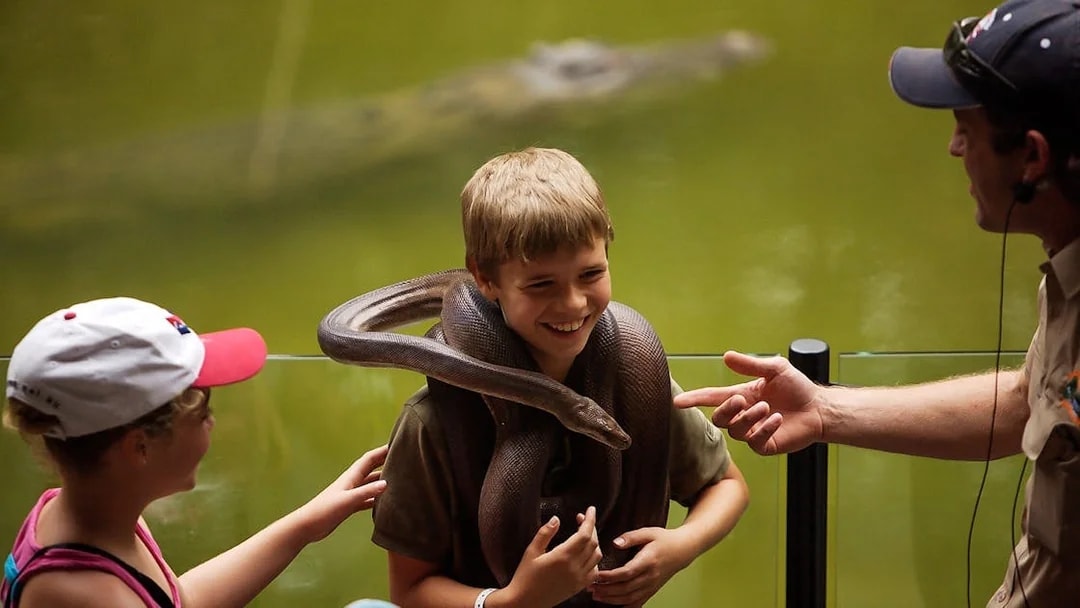 Child with snake at Hartley’s Crocodile Adventures, guided interaction.
