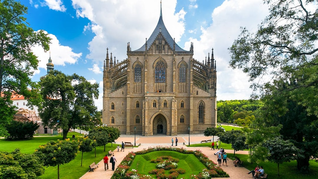 St. Barbara's Church in Kutna Hora with surrounding gardens and visitors.