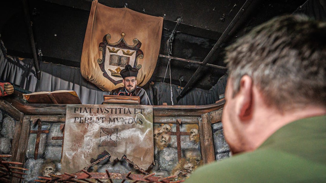 Judge performing act inside Hamburg Dungeon with medieval decor and audience member.