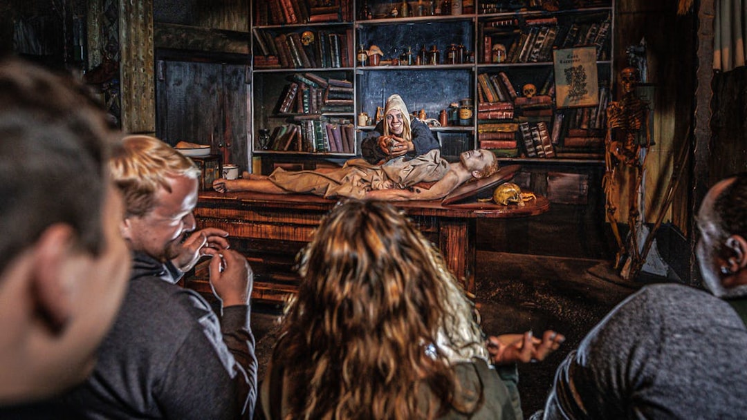 Audience watching Plague act in Hamburg Dungeon with actor and patient on table.