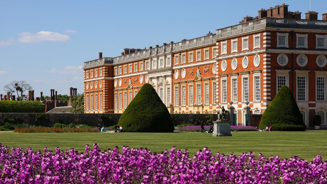 Hampton Court Palace with gardens and purple flowers in London.