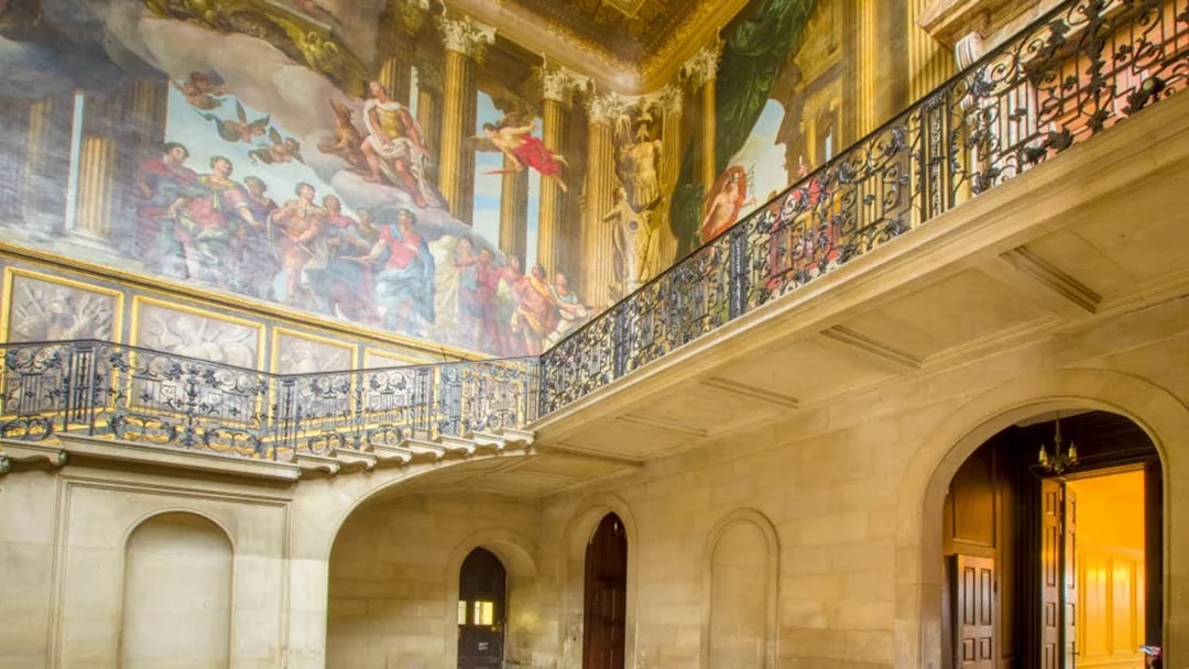Hampton Court Palace interior with ornate ceiling mural and decorative balcony.