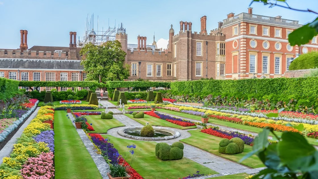 Visitors exploring 20th century gardens at Hampton Court Palace on a sunny day.