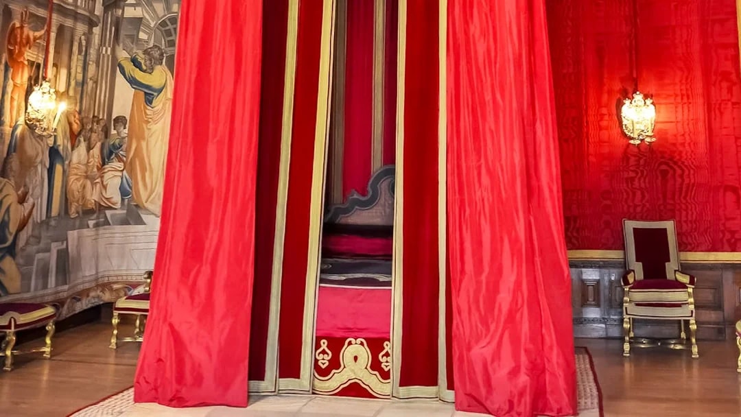 William III’s Apartments at Hampton Court Palace with red drapery and ornate chair.