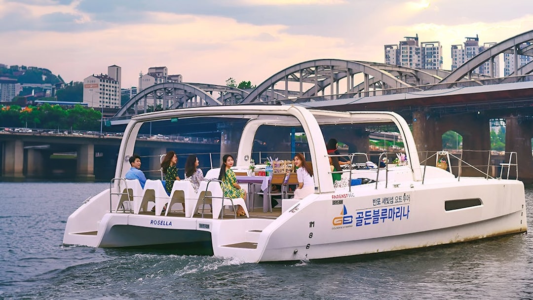 Yacht on Han River with people enjoying a scenic cruise near a bridge in Seoul.