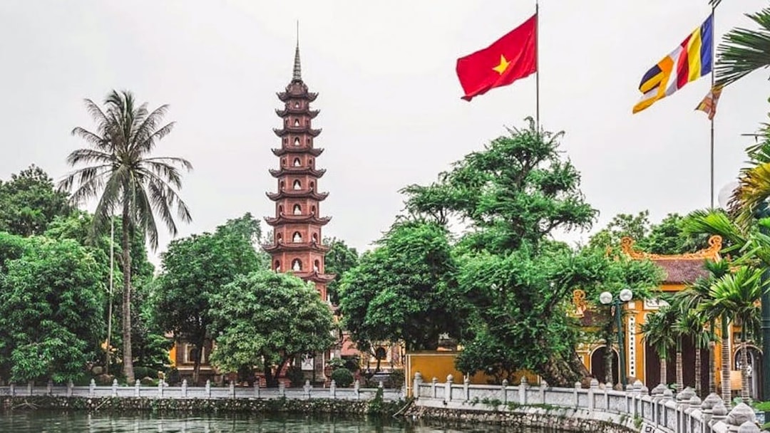 Tran Quoc Pagoda by the lake in Hanoi with Vietnamese flag.