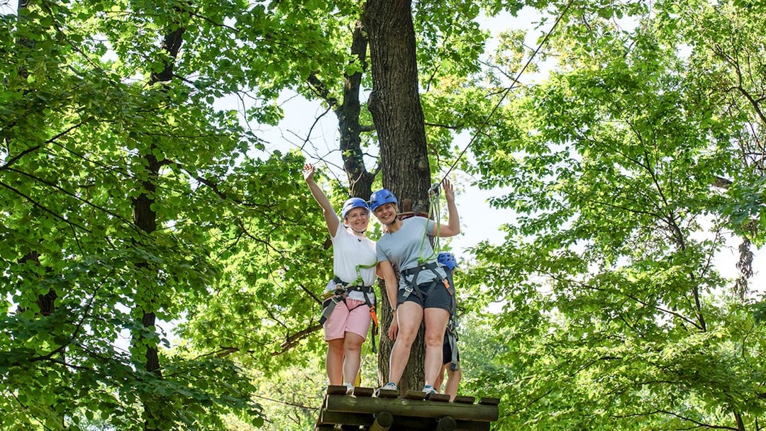 Women on zipline platform at Hanuman World Phuket surrounded by trees.