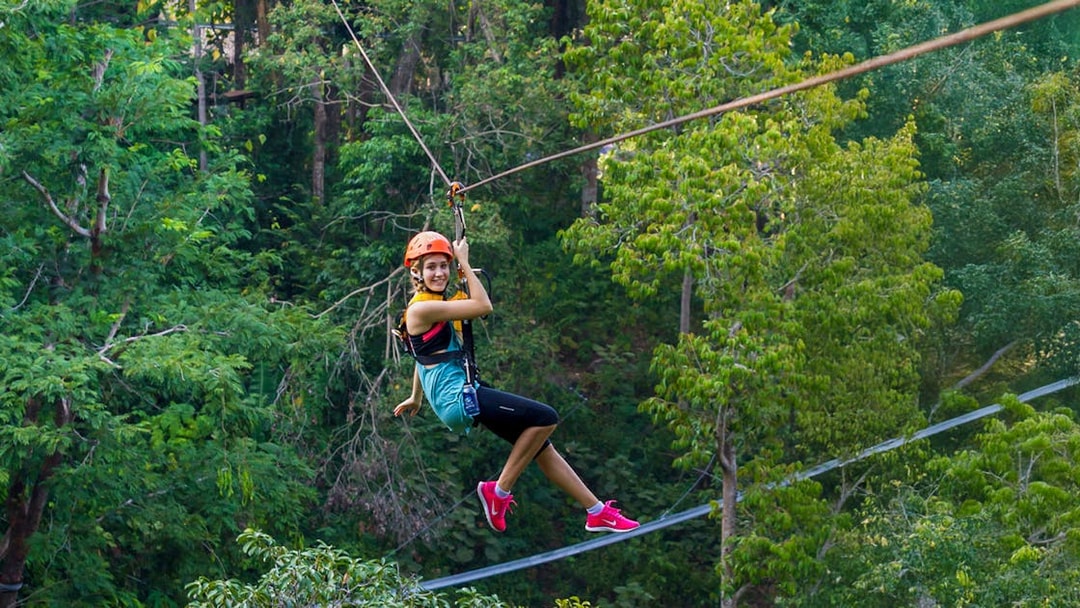 Person ziplining through lush forest at Hanuman World, Phuket.