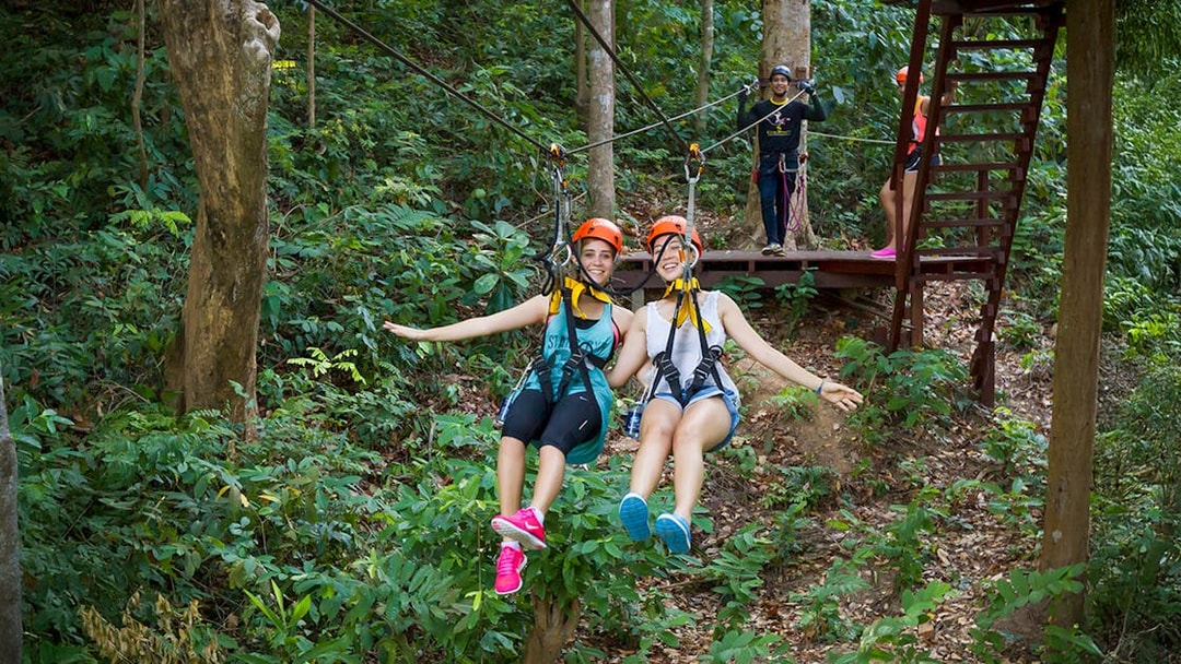 Girls ziplining through forest at Hanuman World, Thailand.
