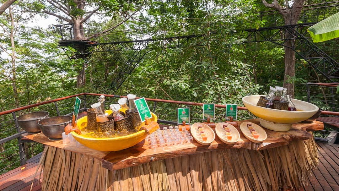 Juices and water on a wooden table at Hanuman World, surrounded by lush greenery.