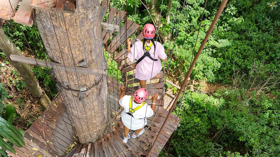 Visitors on a treetop platform at Hanuman World zipline adventure in lush forest.