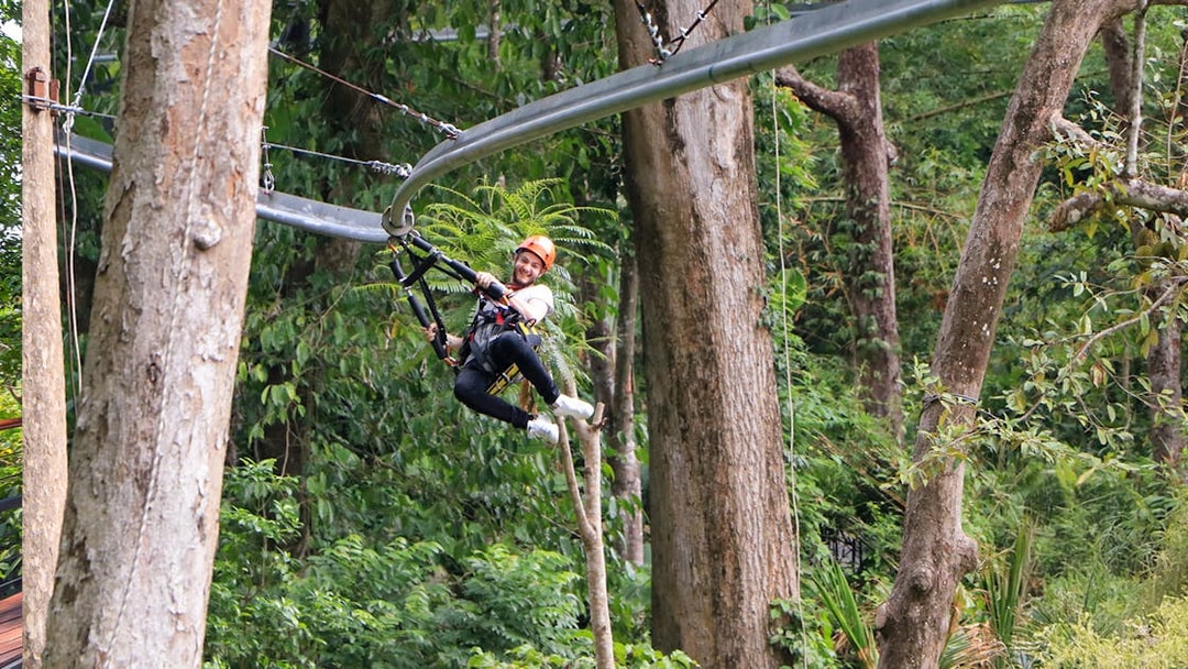 Man ziplining through lush forest in Phuket.
