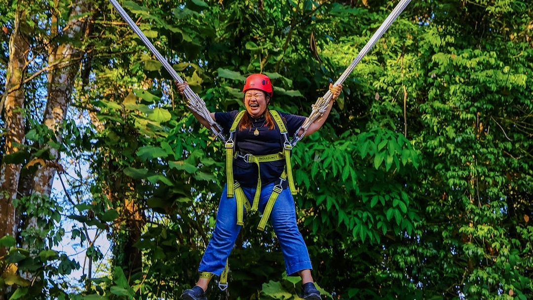 Person enjoying Slingshot Zipline at Hanuman World, surrounded by lush greenery.