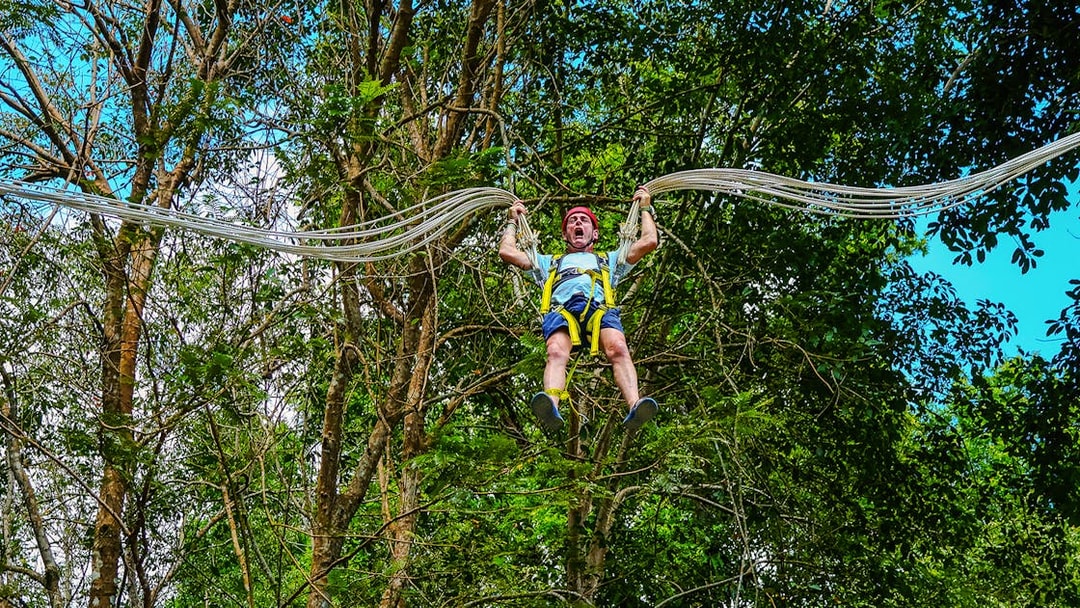 Person enjoying Slingshot Zipline at Hanuman World, surrounded by lush trees.