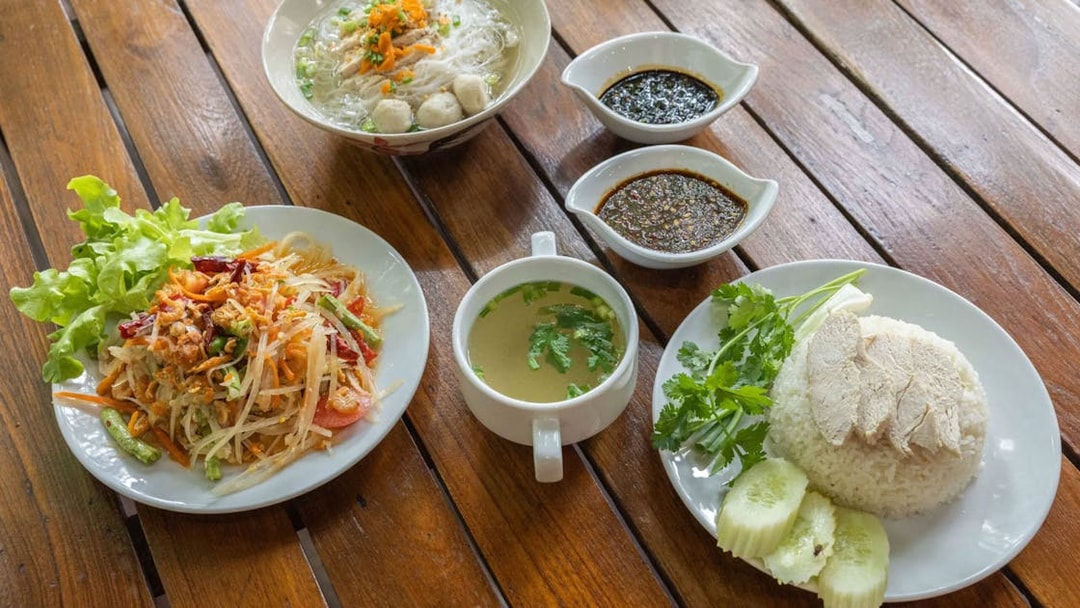 Traditional Thai dishes at Hanuman World buffet, featuring papaya salad, noodle soup, and chicken rice.