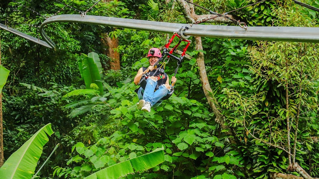 Girl enjoying roller zipline through lush forest.