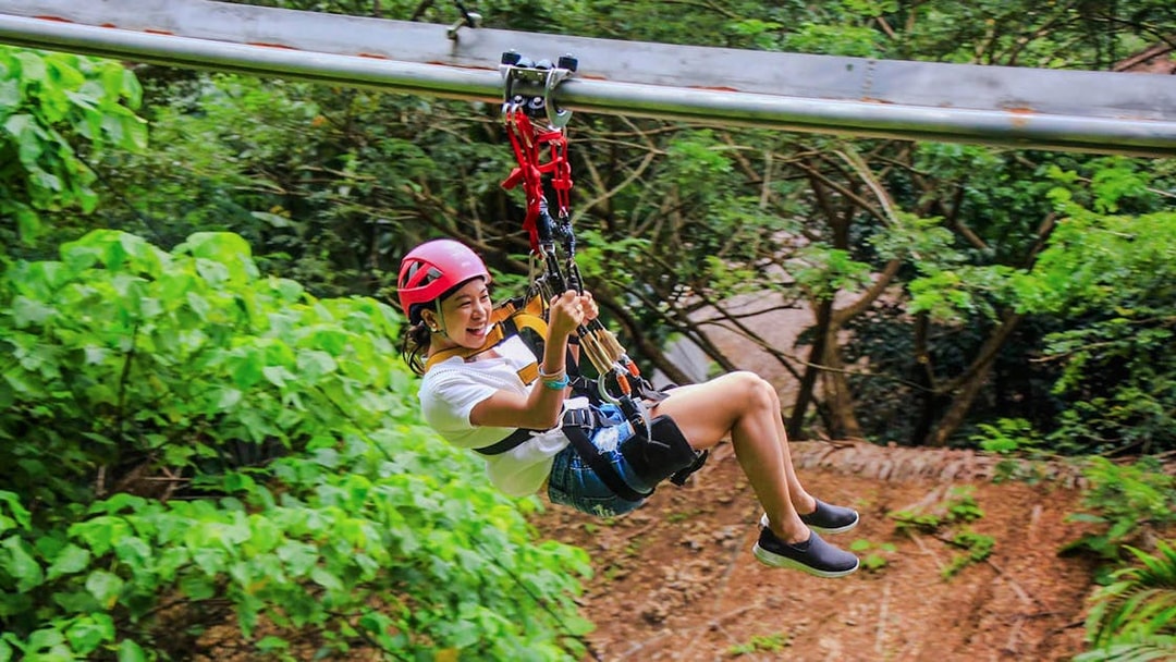 Tourist ziplining at Hanuman World amidst lush greenery.