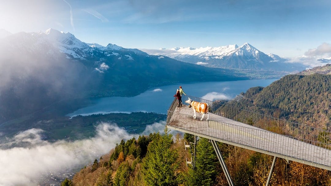 Couple at Two Lakes Bridge viewpoint, Harder Kulm, overlooking mountains and lake.