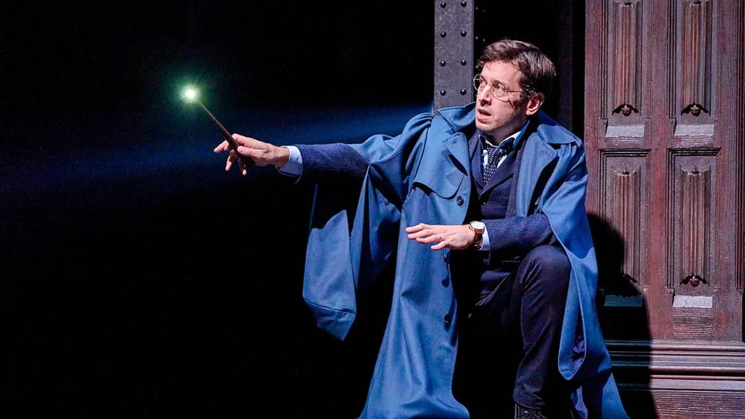 Actor holding a glowing wand in "Harry Potter and the Cursed Child" stage scene.