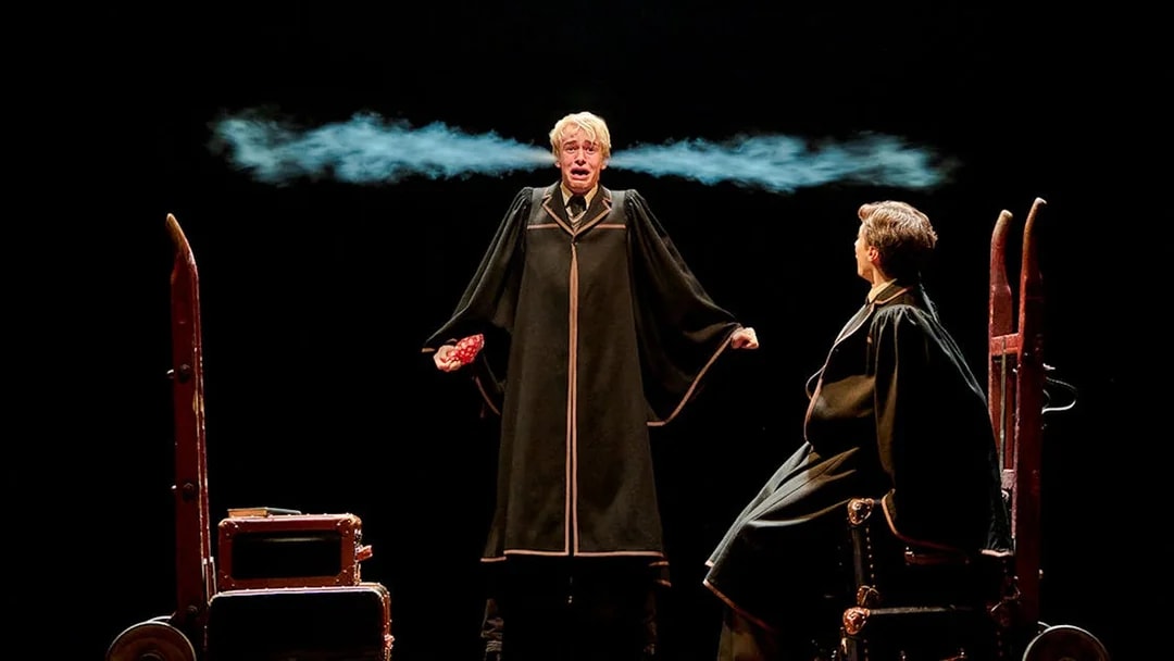 Two actors in wizard robes perform a scene from "Harry Potter and the Cursed Child" on stage.