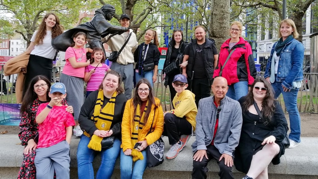 Group of tourists at Harry Potter film location in London with a broomstick statue.