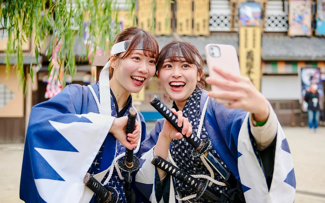Visitors in samurai costumes taking a selfie at Toei Kyoto Studio Park.