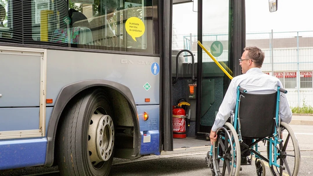 Man in wheelchair boarding a bus via accessible ramp.