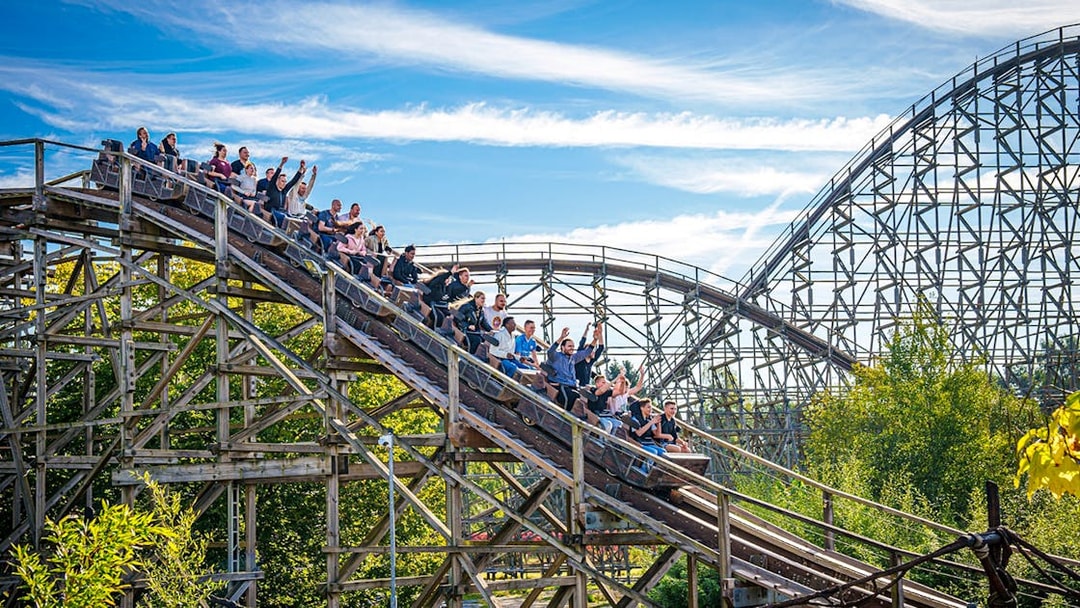 Roller coaster at Heide Park with riders descending a wooden track.