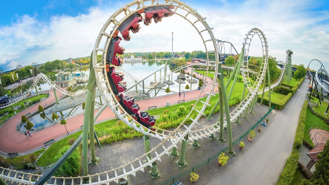 Roller coaster loop at Heide Park with riders and scenic park view.