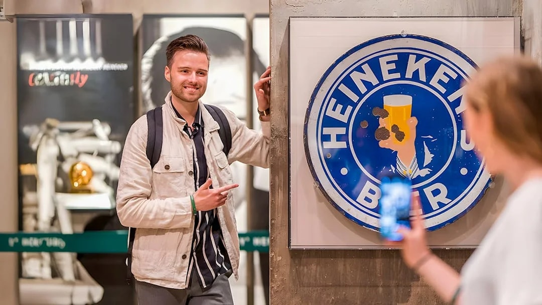 Guests enjoying the Heineken Experience in Amsterdam with a vintage sign.